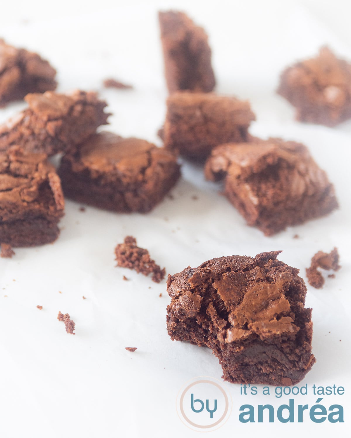 Smeuïge brownies met chocola verdeeld over een tafel. Bij de voorste is er een hapje uitgenomen