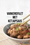 Een grijs schaaltje waar twee chopsticks een blokje varkensfilet uit pakken. Overgoten met een romige ketjapsaus