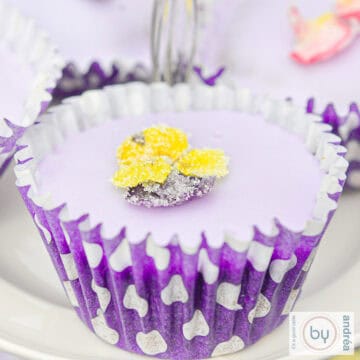 Een vierkante foto met een lavendelcupcake met een gele viooltjes suikerbloem.