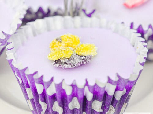 Een vierkante foto met een lavendelcupcake met een gele viooltjes suikerbloem.