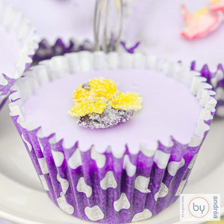 Een vierkante foto met een lavendelcupcake met een gele viooltjes suikerbloem.