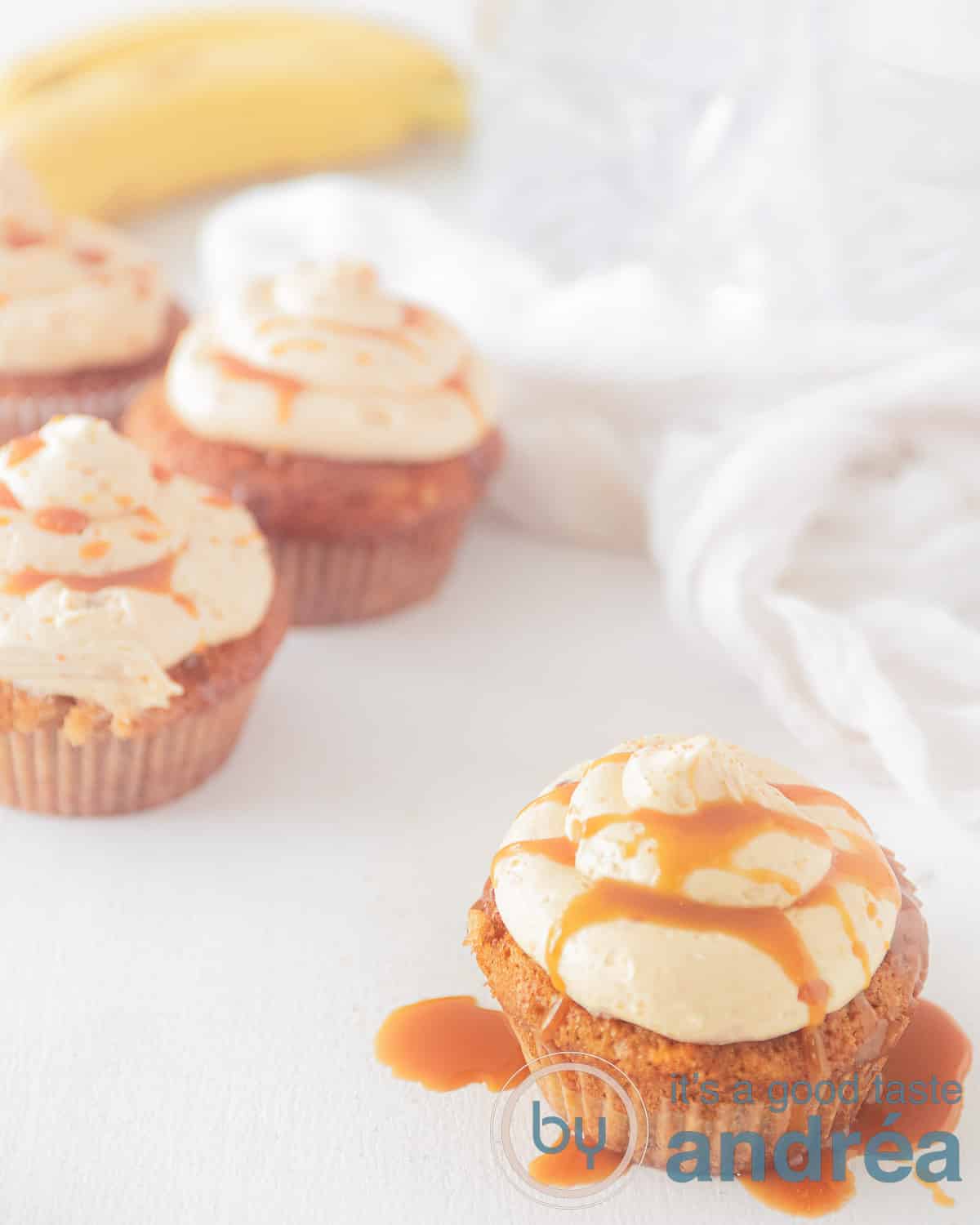 bananen cupcake met karamel botercrème. Eén cupcake op de voorgrond waar de karamel afdruipt de rest op de achtergrond