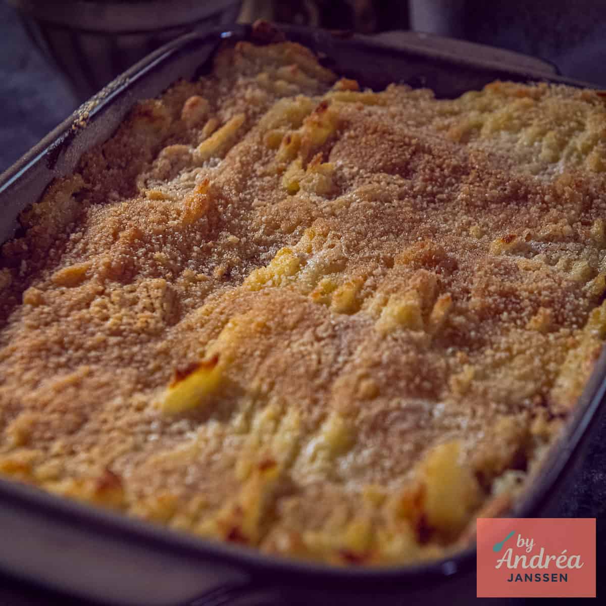 Een vierkante foto met een zuurkool en gehakt ovenschotel met aardappelpuree bovenop.