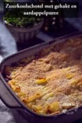 Een deel van een ovenschaal met zuurkool, gehakt en aardappelpuree. Een tekst bovenin: zuurkoolschotel met gehakt en aardappelpuree