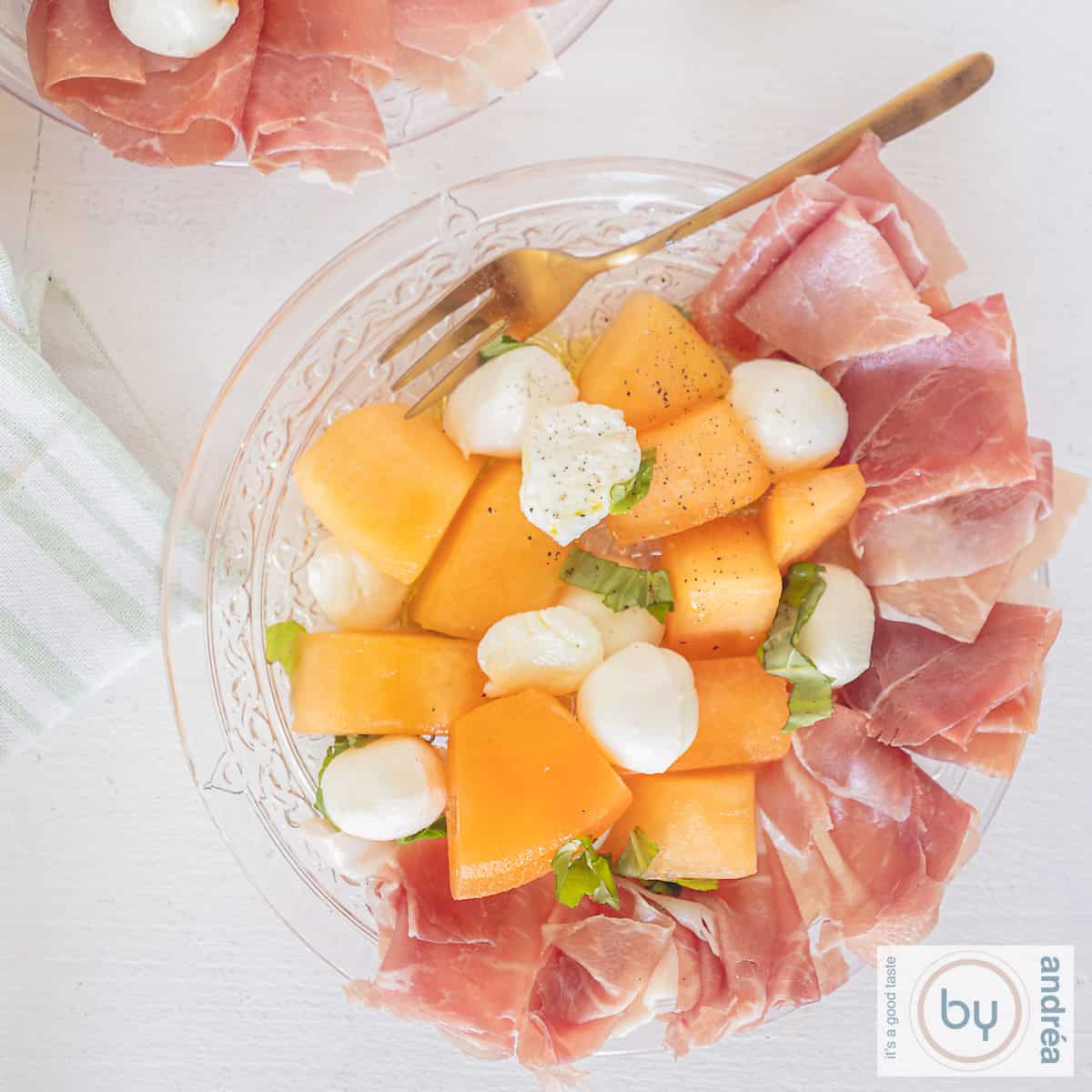 A square picture a glass plate with Parma ham, melon, mozzarella and basil.