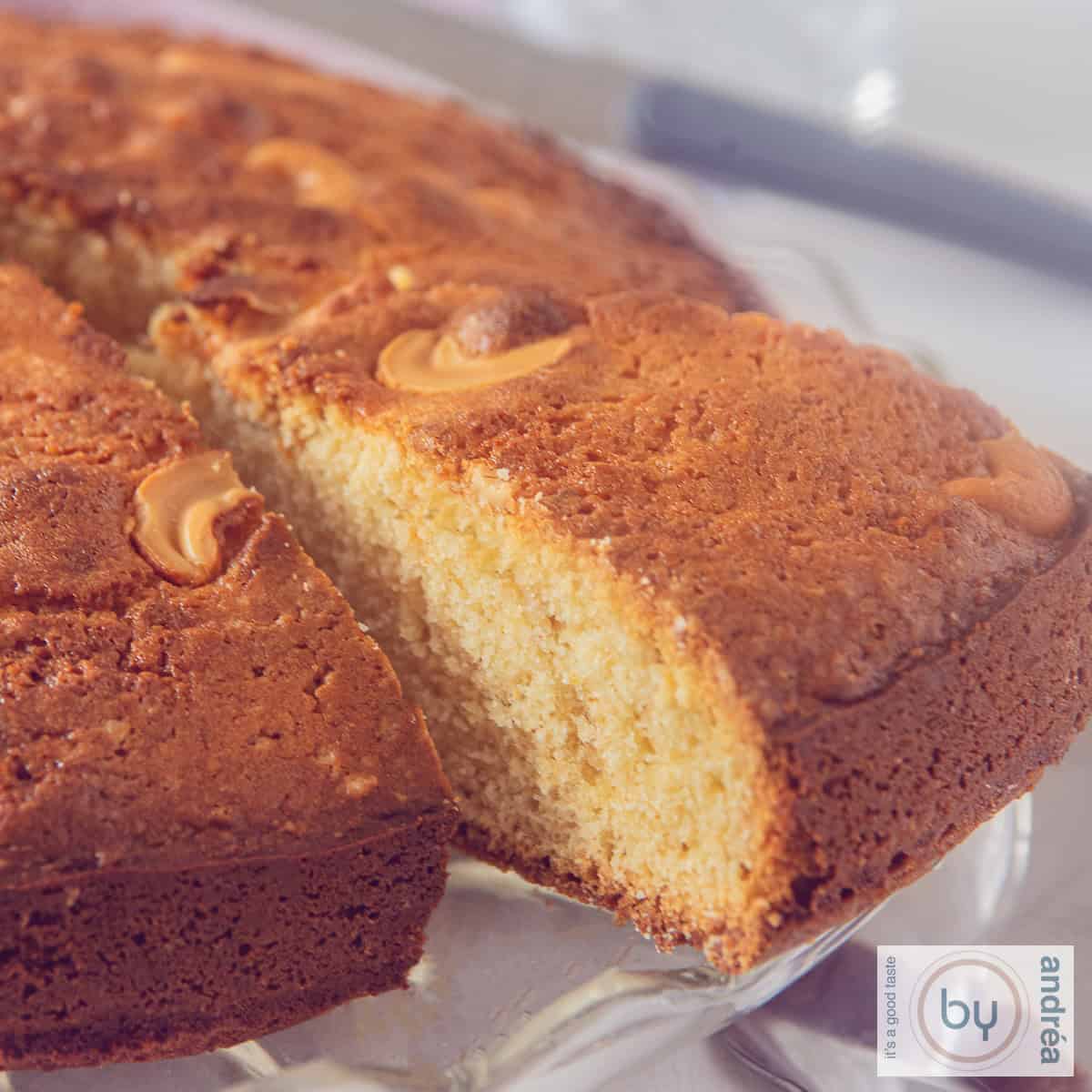 Een vierkante foto van een deel van een Indiase cake met mawa, kardemom en cashewnoten. Een punt eruitgesneden.