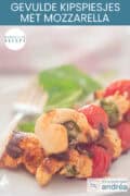 Een deel van een bord met drie spiesen met kipfilet, basilicum, mozzarella en cherrytomaten. Een tekst bovenin: makkelijk recept, gevulde kipspiesjes met mozzarella