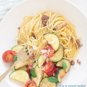 Spaghetti met roerbak courgette op bord met glazen water