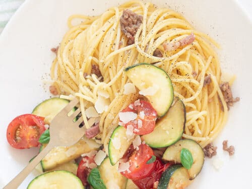 Spaghetti met roerbak courgette op bord met glazen water