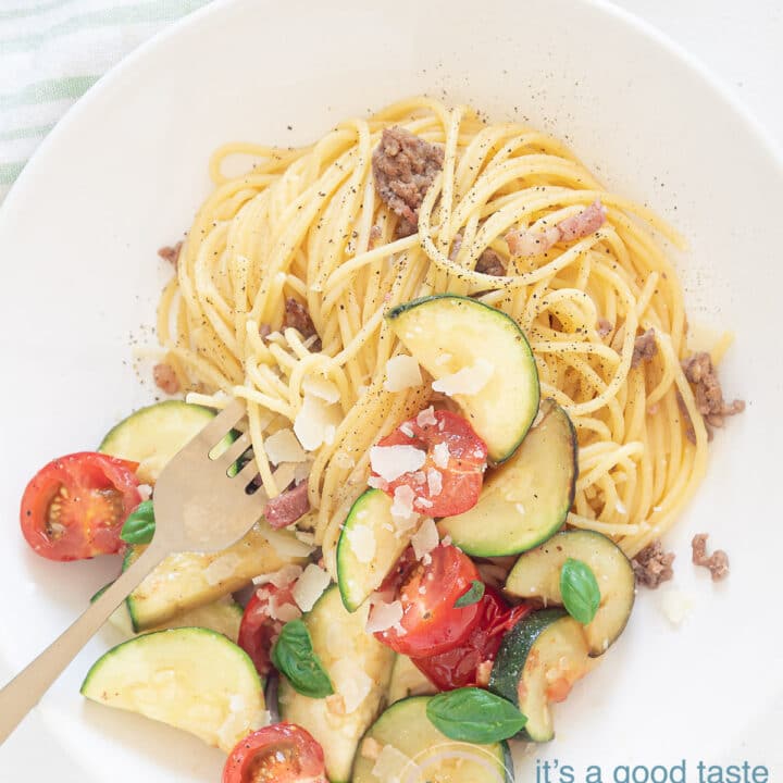 Spaghetti met roerbak courgette op bord met glazen water