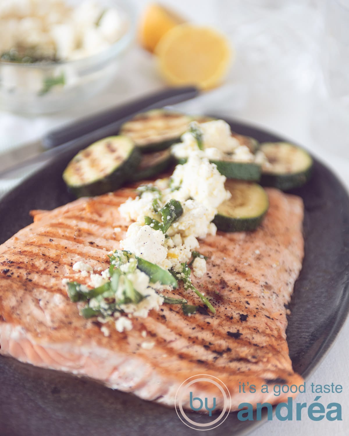 Een zalmmoot met courgette op een grijze schaal, getopt met feta