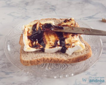 Een snee brood met plakken Camembert, appelstroop wordt erop gesmeerd