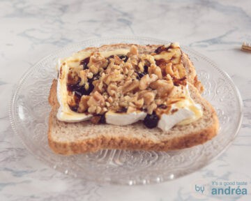 Een snee brood belegd met plakken Camembert, appelstroop en walnoten