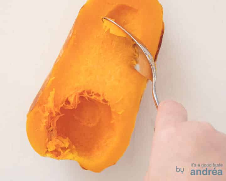 Een halve geroosterde flespompoen wordt uitgeschraapt.