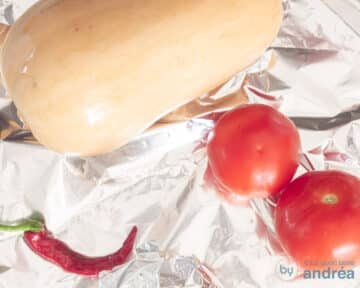 Pompoen, peper en tomaten liggen op aluminiumfolie