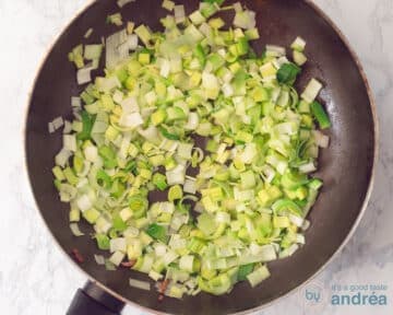 Een pan gevuld met gesmoorde reepjes prei.