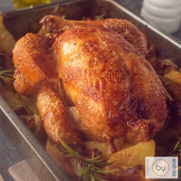 Een vierkante foto van een bakpan met geroosterde kip met aardappeltjes, bacon en rozemarijn