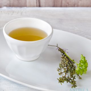 Groentebouillon in een kopje met verse kruiden