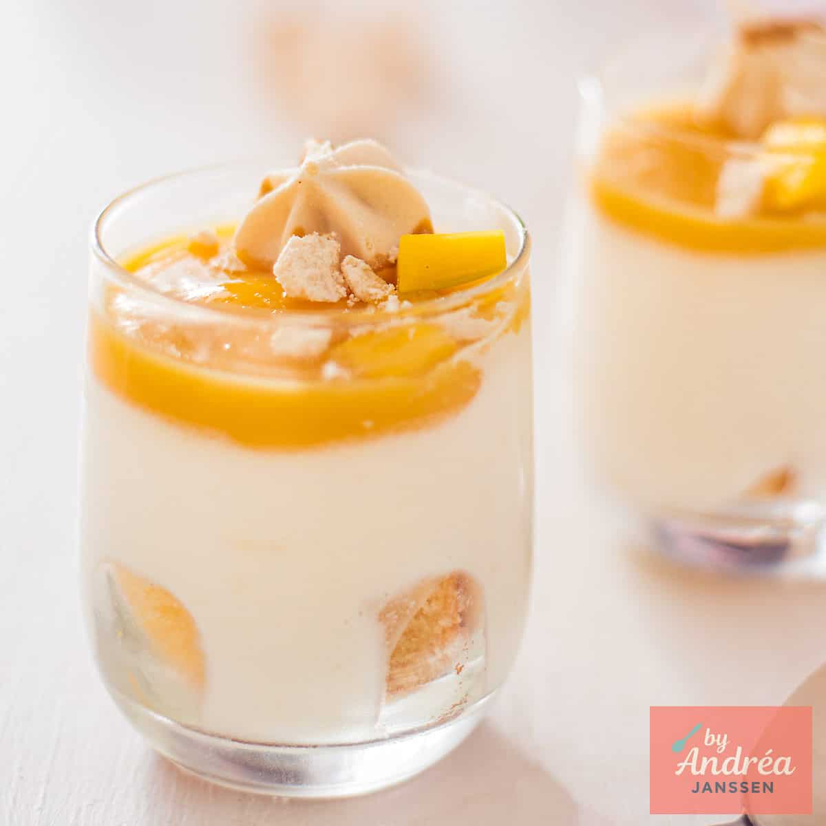 Een vierkante foto met twee glaasjes met Witte Chocolademousse met Mangogelei