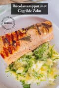 Een foto van bovenaf van een rucolastamppotje met zalm van de grill. Een tekst bovenin: rucolastamppot met gegrilde zalm