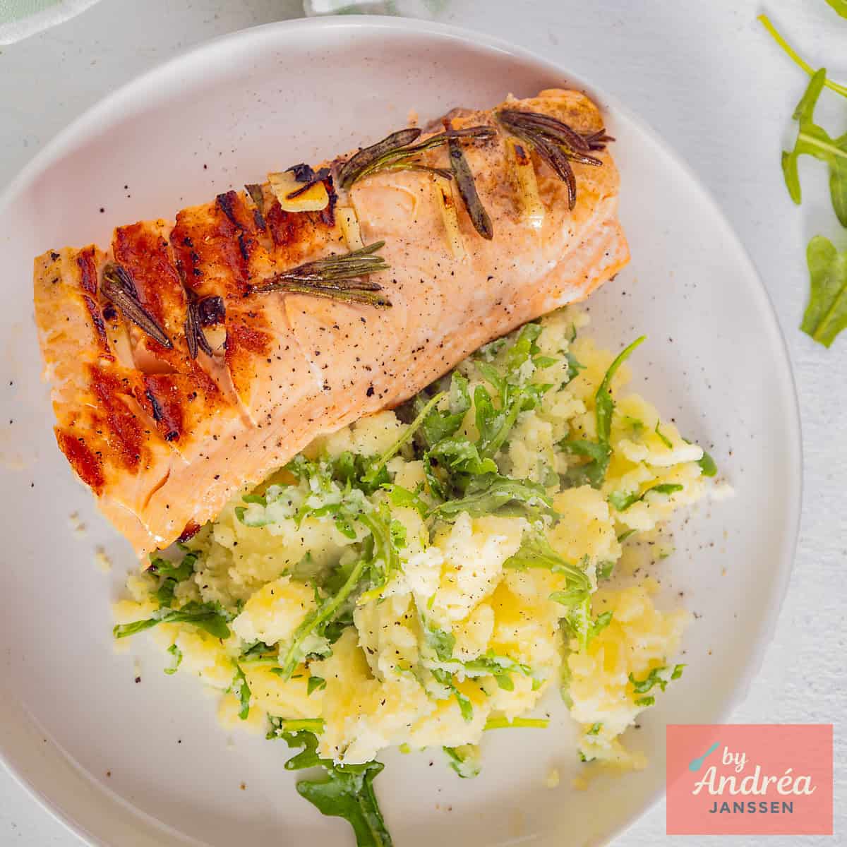 Een vierkante foto van stamppot met rucola en gegrilde zalm