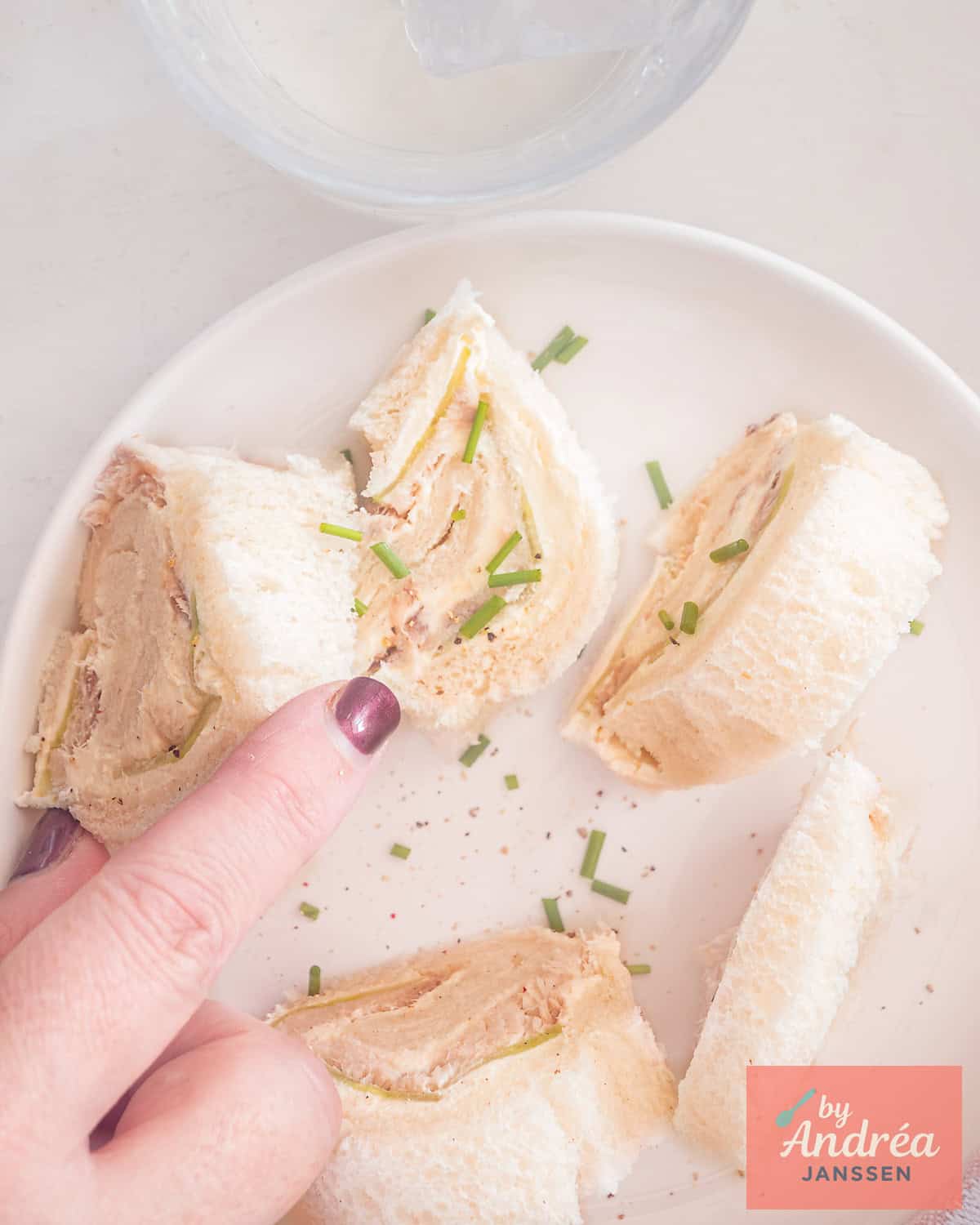 Een foto van bovenaf van een bord met sandwich rolletjes met gerookte makreel en komkommer.