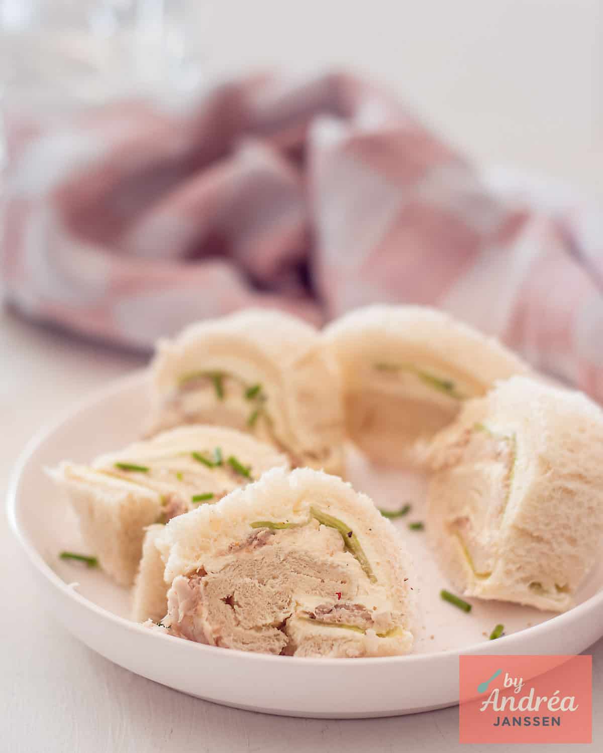 Vijf high tea sandwiches met gerookte makreel en komkommer op een wit bord.