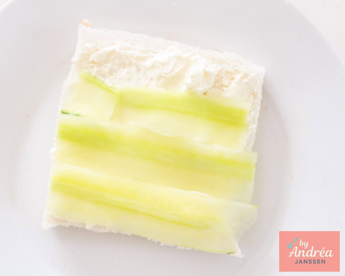 Een sandwich bestreken met crème fraîche waarop komkommer repen zijn gelegd.