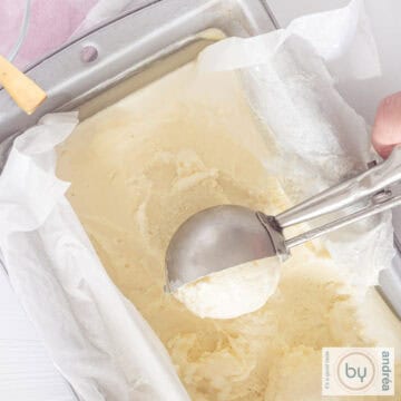 Een vierkante foto van bovenaf van een cakeblik gevuld met chocoladeijs, een ijsschep schept een bolletje