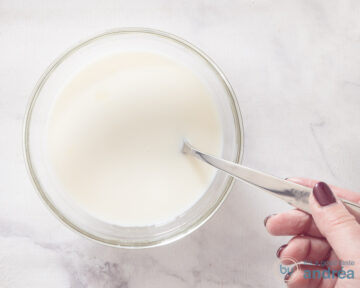 Een schaaltje waarin gecondenseerde zoete melk wordt gemengd met volle melk