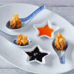 Wontons met rundergehakt op een lepel met twee sausjes