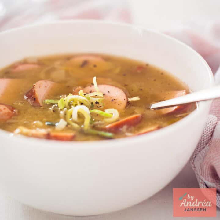 Een vierkante foto met een witte kom met erwtensoep met worst en ham, zoals oma hem maakt.