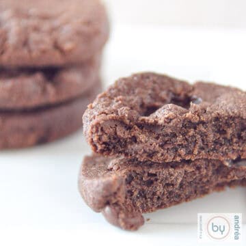 Een vierkante foto met twee halve chocoladekoekjes op elkaar. Er achter een stapeltje van drie world peace cookies