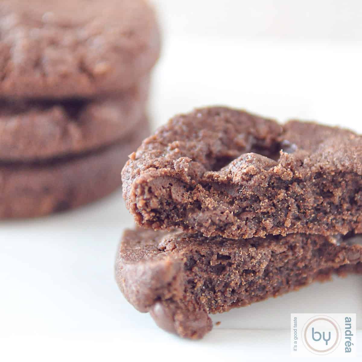 Een vierkante foto met twee halve chocoladekoekjes op elkaar. Er achter een stapeltje van drie world peace cookies
