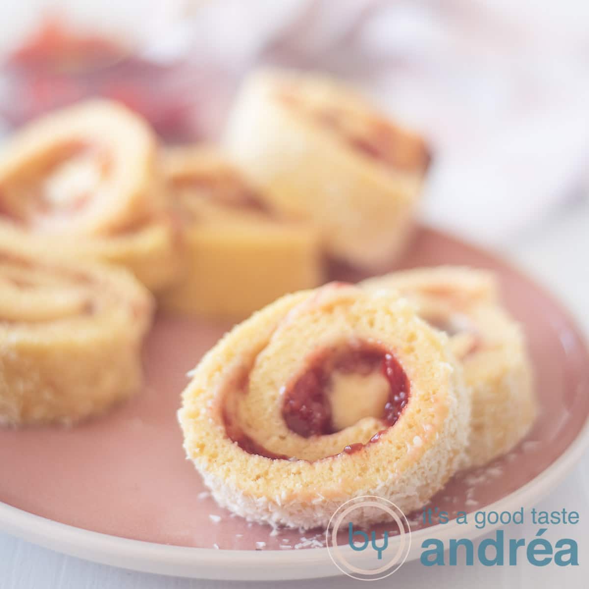 Vierkante foto met een roze bord met cakerolletjes gevuld met jam en botercrème