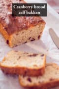 Een cranberry brood met twee sneeen eraf gesneden. Een tekst bovenin: cranberry brood zelf bakken