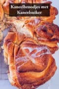 Een deel van een kaneelbrood, een stuk eruit gesneden. Een tekst; kaneelbrood met kaneelsuiker.