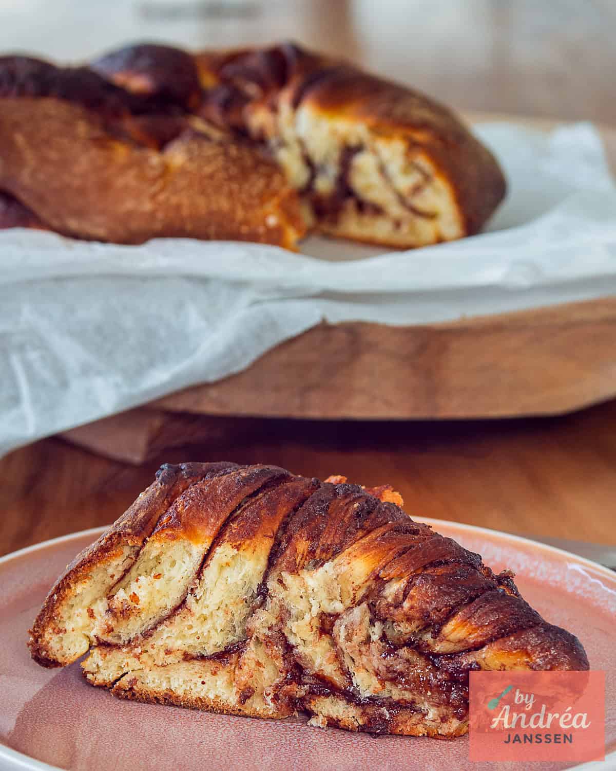 Een partje van het Nutella brood op een bord, de lagen afgewisseld met Nutella goed zichtbaar. In de achtergrond de rest van het brood.