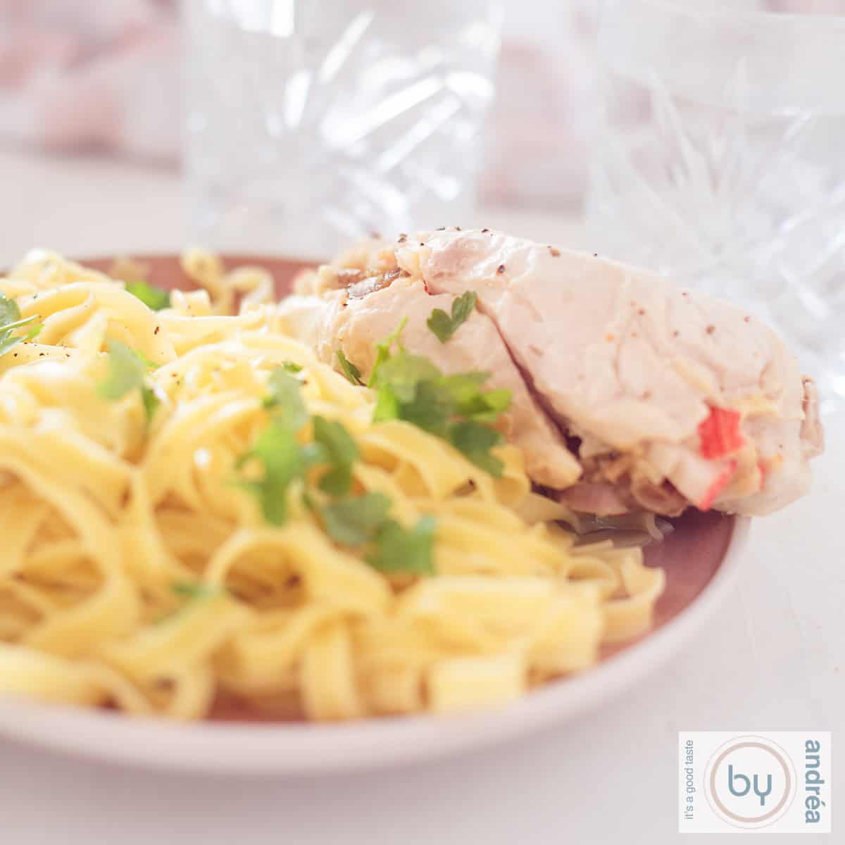 Een vierkante foto met een roze bord met tagliatelle en gevulde kip met dadels en surimi