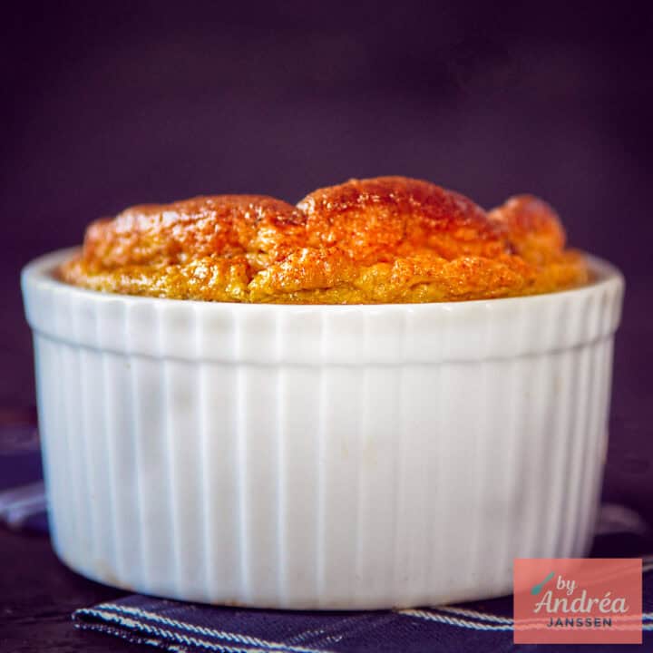 Een vierkante foto van een ramekin waar een aardpeer souffle naar boven is gerezen.