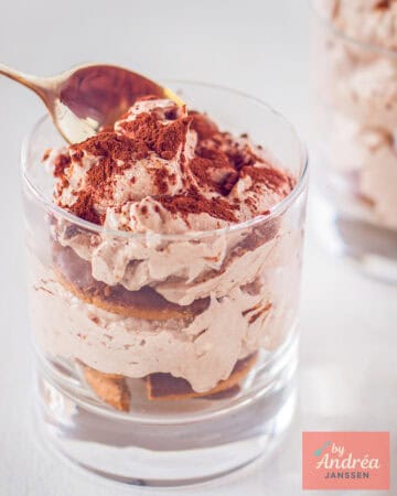 Een glaasje met koffie chocolade tiramisu. Een lepel neemt een hap.