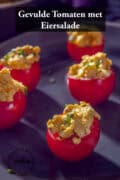 Een bord met gevulde tomaten met eiersalade. Een tekst bovenin: gevulde tomaten met eiersalade