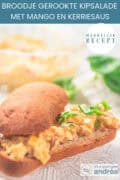 Een glazen schaal met daarop een opengesneden stokbrood met kip-mango salade. Een tekst bovenin: makkelijk recept: broodje gerookte kipsalade met mango en kerriesaus