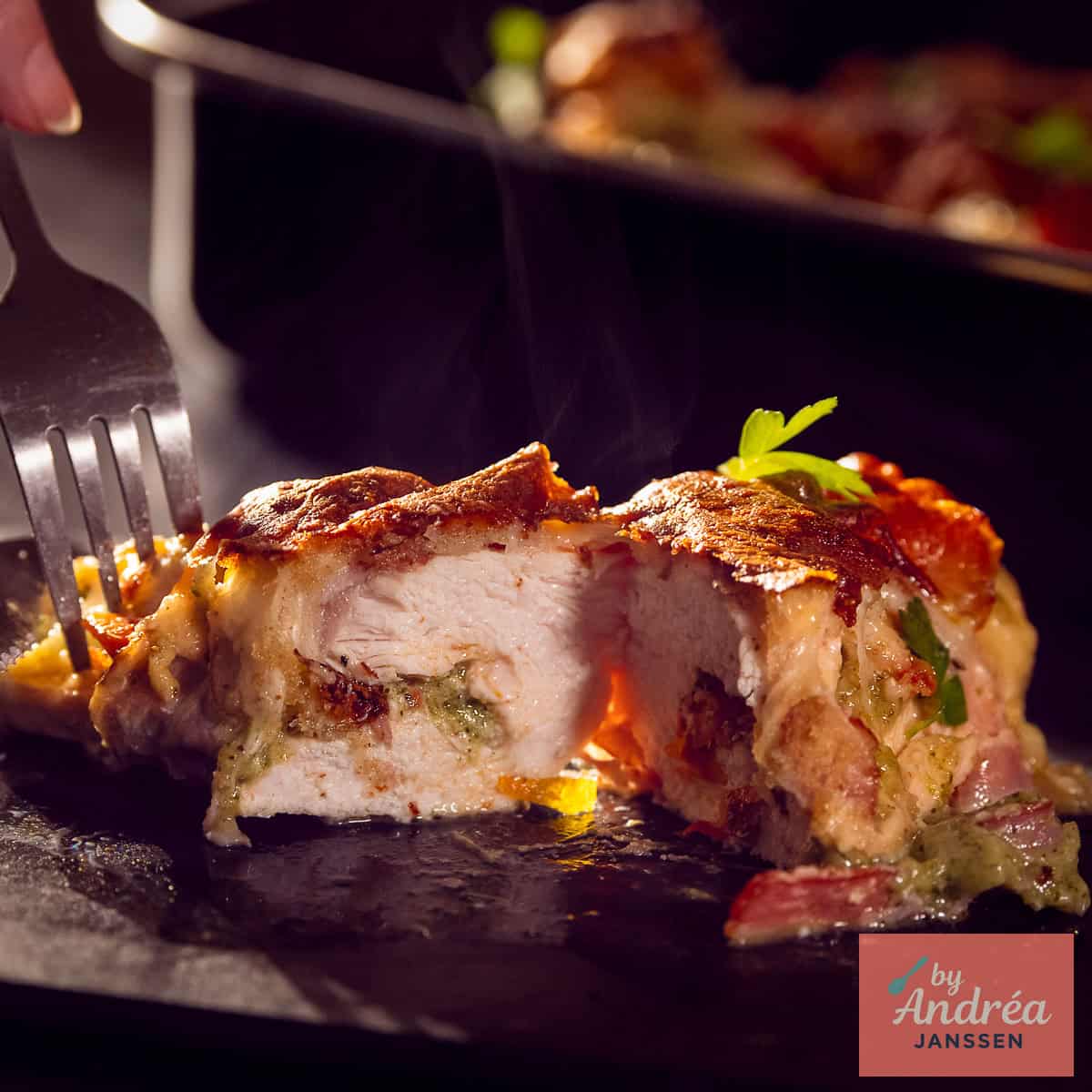 Een vierkante foto met een doorgesneden kipfilet met pesto mozzarella vulling