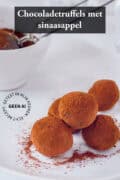 Een schaal met truffels en een bakje cacao in de achtergrond. Een tekst bovenin: Chocoladetruffels met sinaasappel.