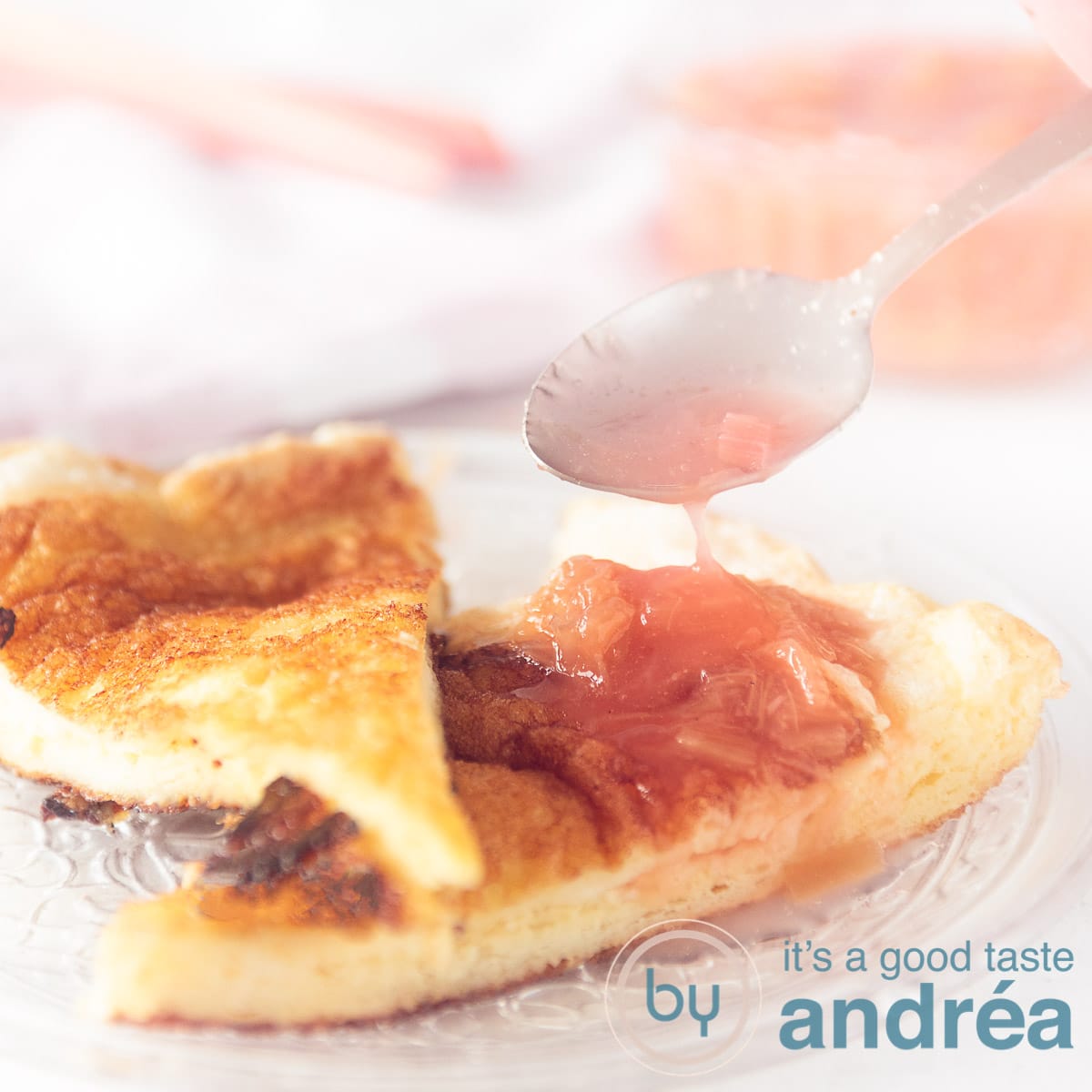 Een vierkante foto met twee puntjes zoete luchtige omelet met rabarber compote. Een lepel schenkt wat rabarbersiroop op de omelet.