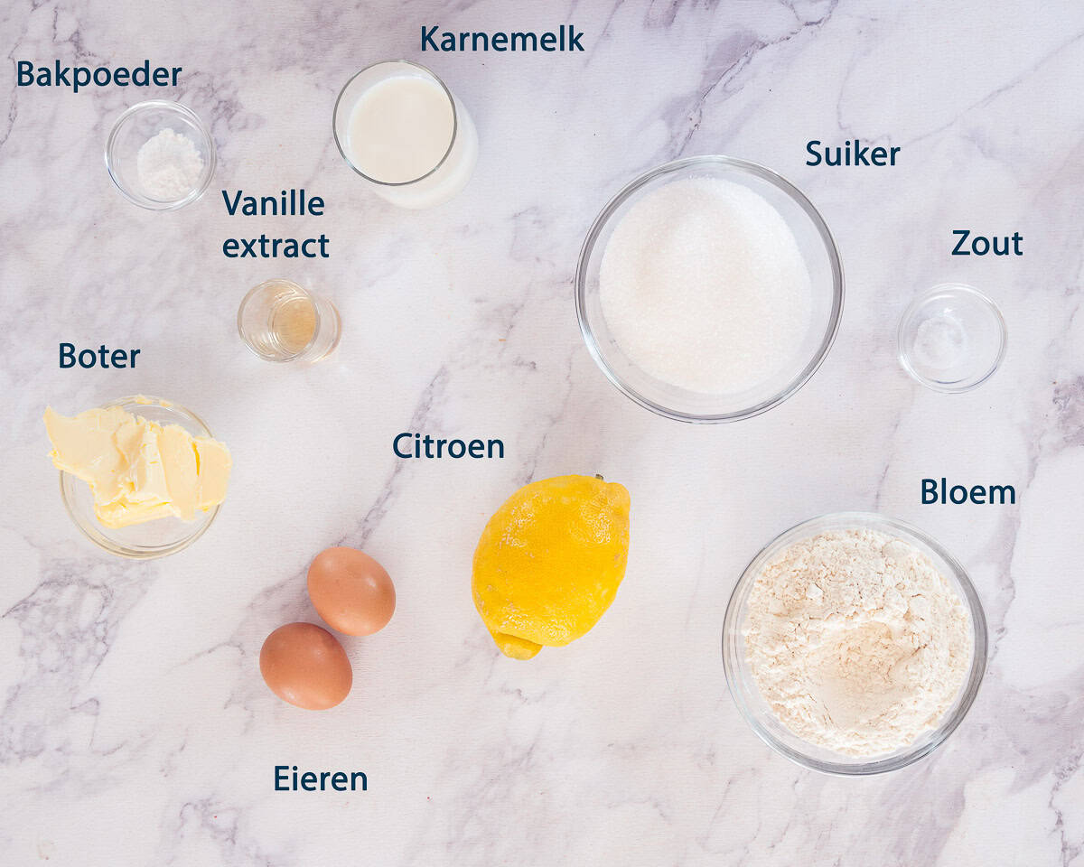 Ingredienten Citroen cupcakes op een wit marmeren ondergrond met tekstbeschrijving