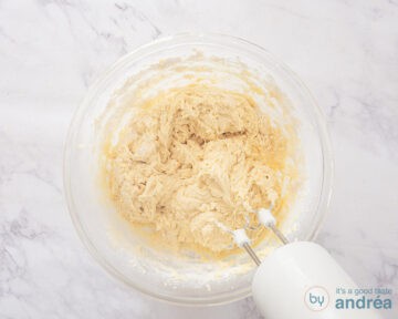Een glazen kom met cupcake beslag en een mixer.