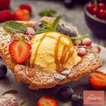 Een vierkante foto met een koekbakje met vanille-ijs met karamelsaus met fruit.