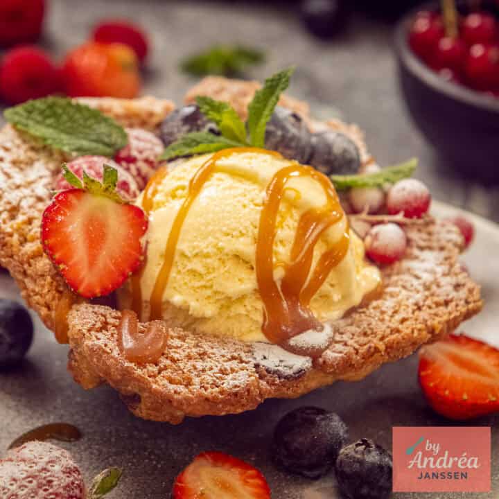 Een vierkante foto met een koekbakje met vanille-ijs met karamelsaus met fruit.
